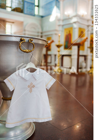 White baptismal dress hanging near baptismal font in church White baptismal dress hanging near baptismal font in church 134331625