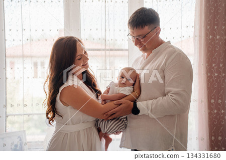 Happy family enjoys a quiet moment at home with baby Happy family enjoys a quiet moment at home with baby 134331680