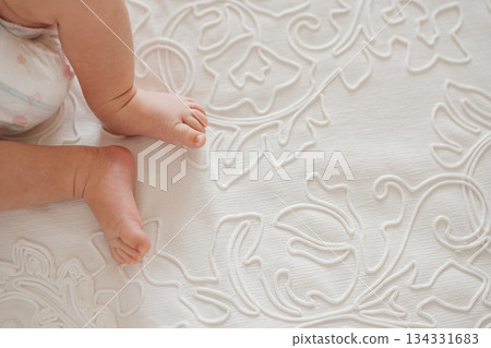 Baby feet on a soft embroidered blanket in a cozy room 134331683