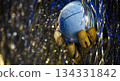 Wooden mannequin hand holding a blue orb amidst shimmering tinsel and bokeh lights 134331842