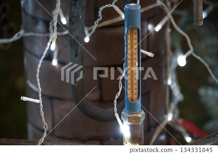 Outdoor thermometer shows freezing temperatures amidst festive holiday lights and pipes 134331845