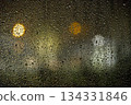 Rainy Glass Night With Bokeh Lights and Droplets Creating Moody Urban Scene Through Street View 134331846