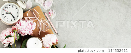 Feminine Workspace with Clock, Flowers, and Stationery 134332411