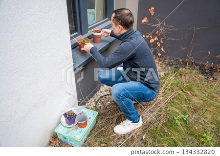 Man prepares flower pots in garden near house. Concept of spring planting and gardening hobby. 134332820