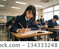 A scene of a classroom with a female high school student in uniform earnestly working on her answer sheet during the National Center Test for University Admissions and mock exams [Generative AI] 134333248