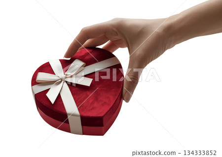 Person holding classic red heart-shaped gift box with white bow, symbolizing love, affection, and thoughtful presents for a special occasion 134333852
