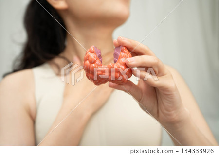 Hyperthyroidism, Overactive Thyroid, Thyroid Lymphoma, Asian woman with thyroid gland human anatomy model. Hyperthyroidism, Overactive Thyroid, Thyroid Lymphoma, Asian woman with thyroid gland human anatomy model. 134333926