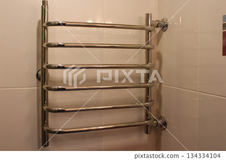 Chrome heating radiator on the wall in the bathroom Chrome heating radiator on the wall in the bathroom 134334104