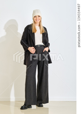 Fashionable young woman in stylish outfit stands confidently indoors with natural light Fashionable young woman in stylish outfit stands confidently indoors with natural light 134334497