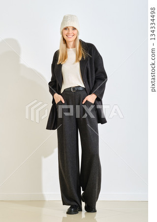 Woman in casual winter outfit poses with confidence in a minimalistic indoor space 134334498
