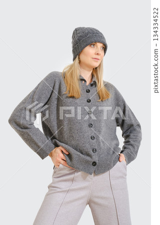 Woman models casual gray cardigan and matching hat in studio setting during daytime 134334522