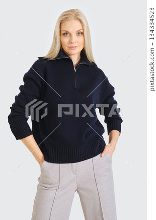 Model poses in stylish navy sweater with half zipper and light gray pants for a modern fashion look Model poses in stylish navy sweater with half zipper and light gray pants for a modern fashion look 134334523