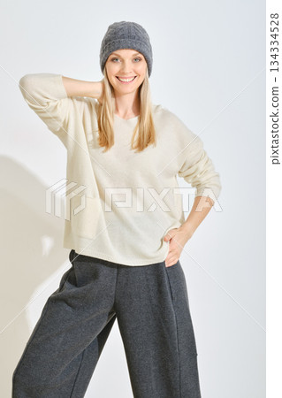 Stylish woman in cozy outfit poses happily in a bright indoor setting with soft lighting Stylish woman in cozy outfit poses happily in a bright indoor setting with soft lighting 134334528