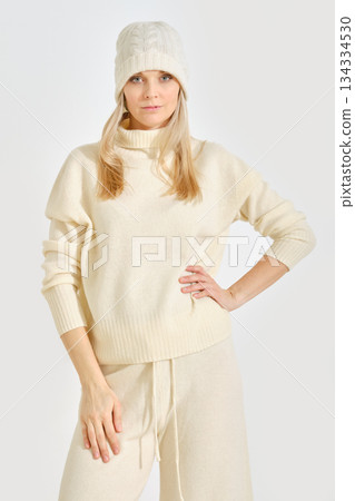 Stylish model showcasing cozy winter fashion in soft neutral tones for seasonal trends 134334530