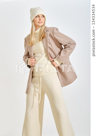 Fashion model showcases stylish winter outfit in neutral tones during indoor photoshoot 134334534
