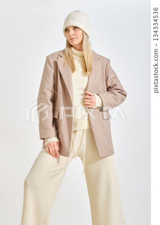 Stylish woman showcasing winter fashion in a soft-toned outfit and knitted hat Stylish woman showcasing winter fashion in a soft-toned outfit and knitted hat 134334536