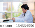 Senior asian doctor writing prescription or document on clipboard in clinic office. 134334550