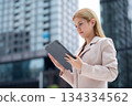 Young caucasian businesswoman reading on digital tablet outdoors in city. 134334562