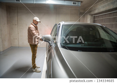 Man approaching parked car in underground garage. Routine parking and transportation habits. Man approaching parked car in underground garage. Routine parking and transportation habits. 134334685