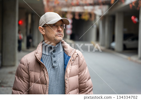 Portrait of a man standing outside in winter clothes. Casual moment outdoors in urban environment. Portrait of a man standing outside in winter clothes. Casual moment outdoors in urban environment. 134334702
