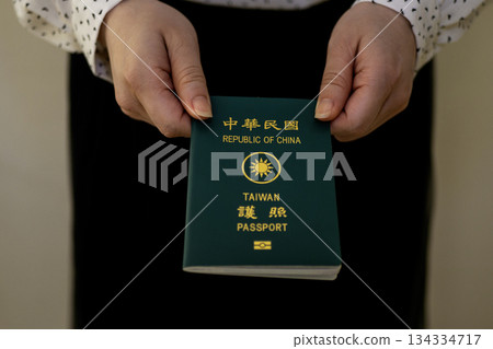 A woman's hand handing over a Taiwanese passport 134334717