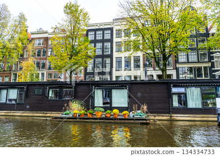 A floating house in Amsterdam canal. Boat home on water. Houseboat in Netherlands 134334733