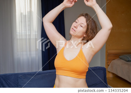 Woman stretching arms up, eyes closed, feeling good in bedroom Woman stretching arms up, eyes closed, feeling good in bedroom 134335204