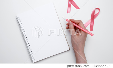 Symbolizing breast cancer awareness. Woman scheduling preventive checkup with visible pink ribbon 134335328