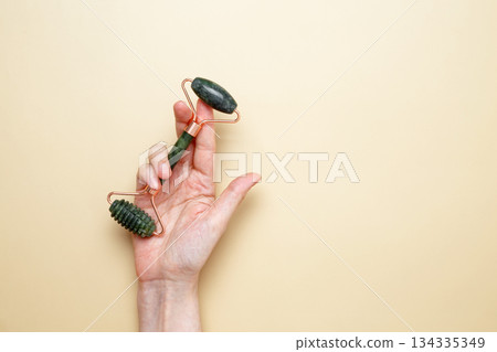 Female hands holding marble face roller tools for skincare routine Female hands holding marble face roller tools for skincare routine 134335349
