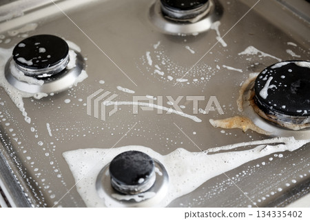 Cleaning dirty gas stove with foamy detergent in kitchen Cleaning dirty gas stove with foamy detergent in kitchen 134335402