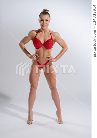 Muscular woman showcases fitness and confidence in vibrant lingerie 134335914