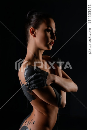 Woman with artistic body paint showcasing elegance against dark backdrop 134335951