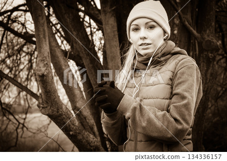 Woman wearing sportswear exercising outside during autumn 134336157