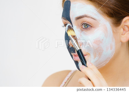 Girl black mask on half face apply white mud Girl black mask on half face apply white mud 134336445