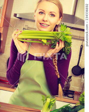Woman in kitchen holds green celery Woman in kitchen holds green celery 134336692