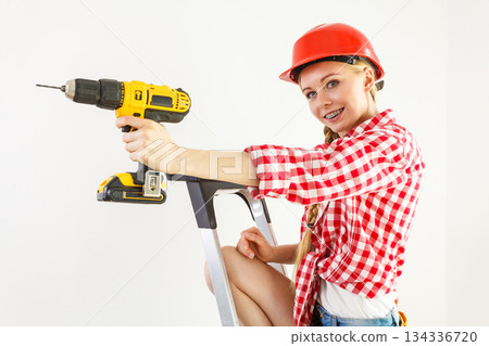 Woman using drill on ladder Woman using drill on ladder 134336720