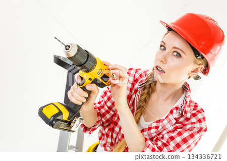 Woman using drill on ladder Woman using drill on ladder 134336721