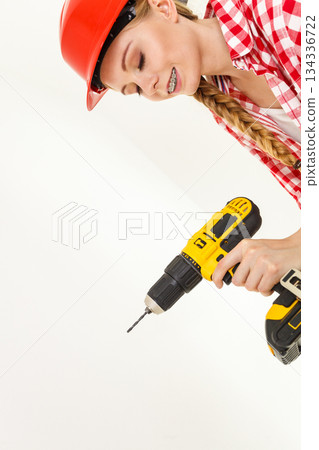Woman using drill on ladder Woman using drill on ladder 134336722