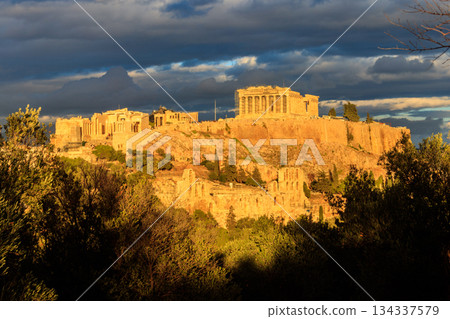 View of the Acropolis Hill, crowned with Parthenon during evening golden hour from the Philopappos Hill in Athens, Greece View of the Acropolis Hill, crowned with Parthenon during evening golden hour from the Philopappos Hill in Athens, Greece 134337579