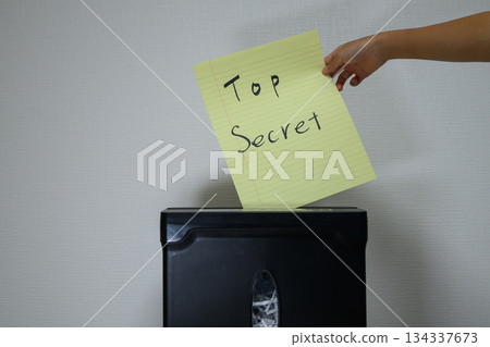 Hands shredding documents marked as top secret Hands shredding documents marked as top secret 134337673