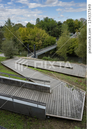 Walkway near river in Mont de Marsan surrounded by greenery and bridges 134337849