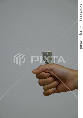 Hand holding a key and a gray background Hand holding a key and a gray background 134338023