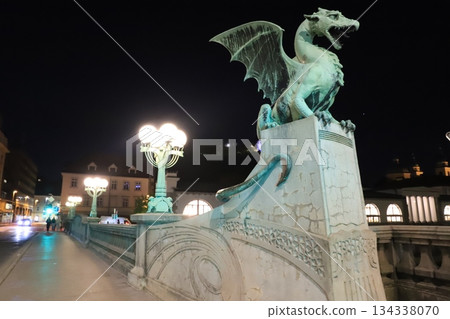 A stone dragon statue standing on the railing of the Dragon Bridge in the center of Ljubljana, the capital of Slovenia A stone dragon statue standing on the railing of the Dragon Bridge in the center of Ljubljana, the capital of Slovenia 134338070
