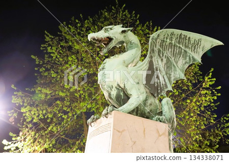 A stone dragon statue standing on the railing of the Dragon Bridge in the center of Ljubljana, the capital of Slovenia A stone dragon statue standing on the railing of the Dragon Bridge in the center of Ljubljana, the capital of Slovenia 134338071