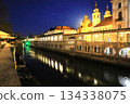 View of the Central Market and St. Nicholas Cathedral at night from the Ljubljanica River in Ljubljana, Slovenia 134338075