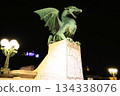 A stone dragon statue standing on the railing of the Dragon Bridge in the center of Ljubljana, the capital of Slovenia 134338076