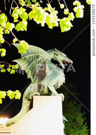 A stone dragon statue standing on the railing of the Dragon Bridge in the center of Ljubljana, the capital of Slovenia 134338078