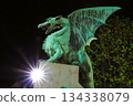 A stone dragon statue standing on the railing of the Dragon Bridge in the center of Ljubljana, the capital of Slovenia 134338079
