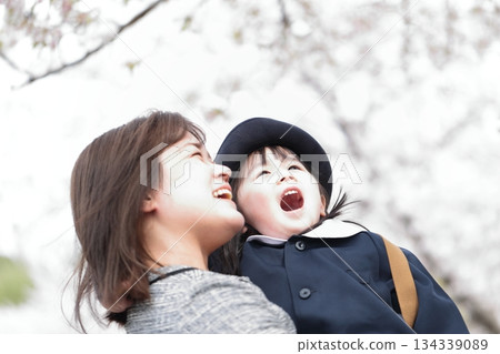 Cherry blossoms and a 3-year-old girl and her mother at the kindergarten entrance ceremony 134339089