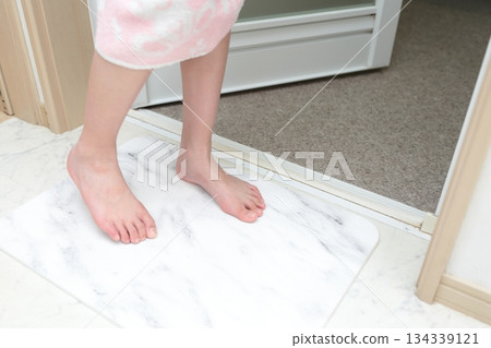 一個女孩正在用矽藻土浴墊擦腳。 134339121